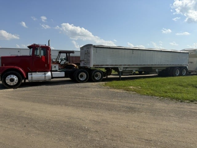 Case tractor loader backhoe parked beside semi truck